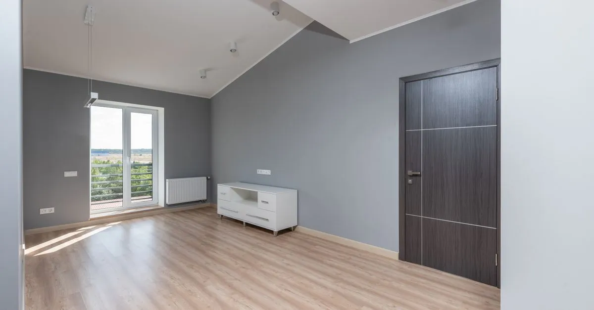 Bright and empty modern room with hardwood floors and large window view.